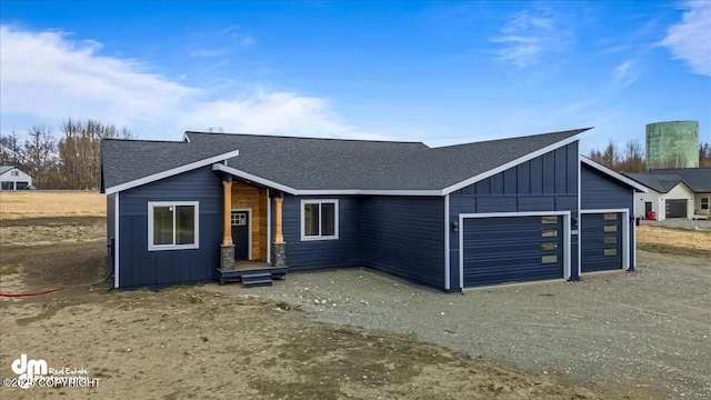 view of front of property with roof with shingles, board and batten siding, dirt driveway, and a garage
