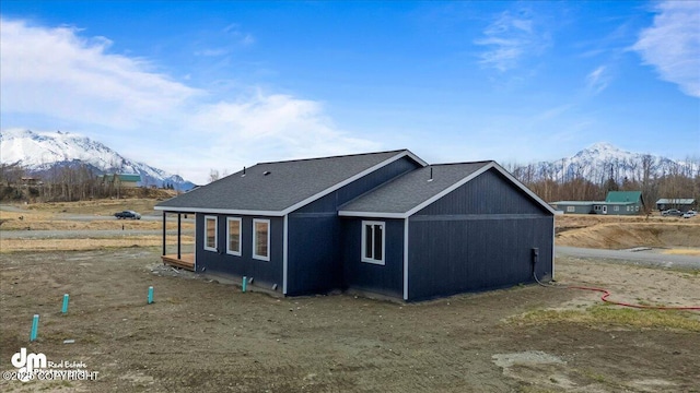 view of property exterior with a mountain view and a shingled roof