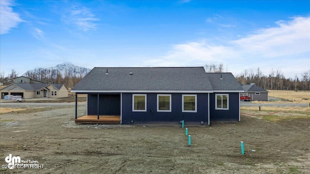 back of house with a mountain view and a shingled roof