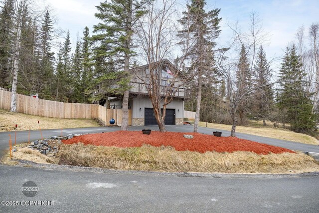 view of front of property with an attached garage, fence, stone siding, and aphalt driveway