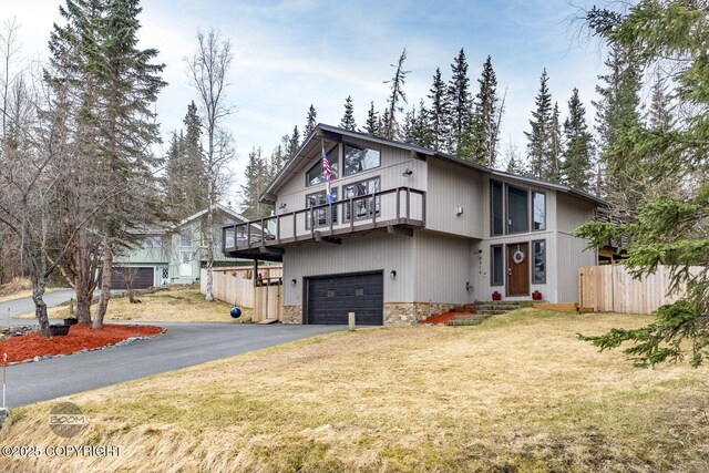 view of front of home featuring fence, an attached garage, stone siding, aphalt driveway, and a front yard