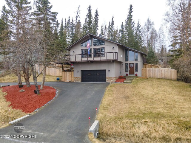 view of front of house with an attached garage, fence, stone siding, and aphalt driveway