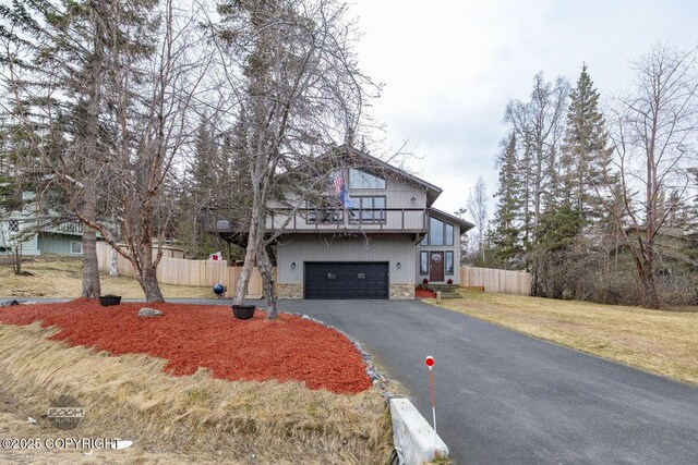 view of front of property featuring fence, an attached garage, driveway, and a balcony