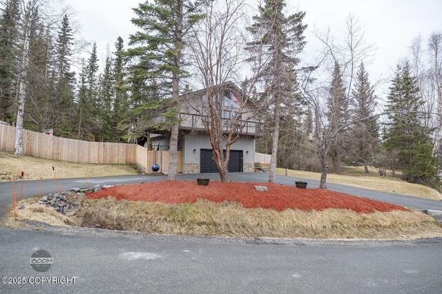 view of front facade with fence, driveway, and stone siding