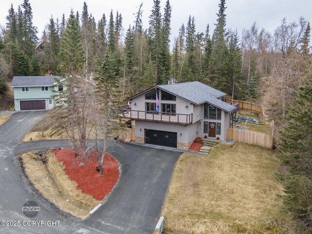 view of front of house featuring a garage, driveway, a chimney, and a forest view