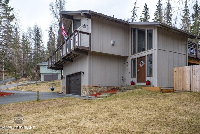 view of front facade with aphalt driveway, a garage, fence, and a front lawn