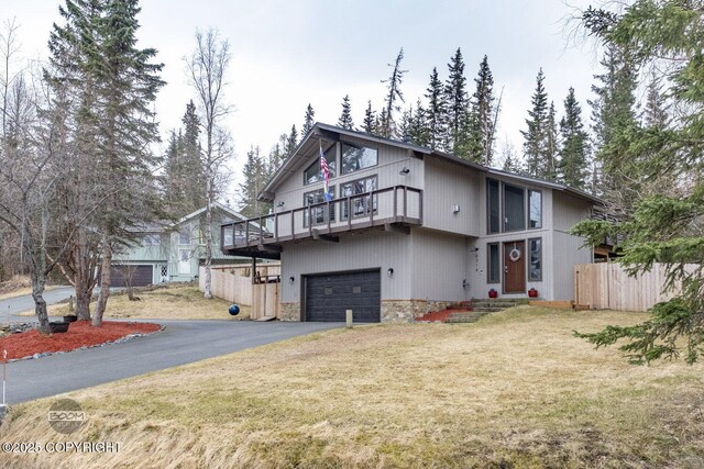 view of front facade featuring a front yard, a garage, fence, aphalt driveway, and stone siding