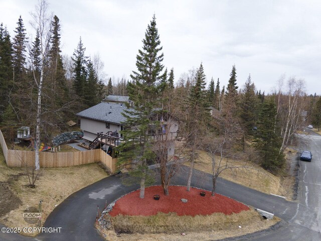 view of front facade featuring a view of trees, fence, and driveway