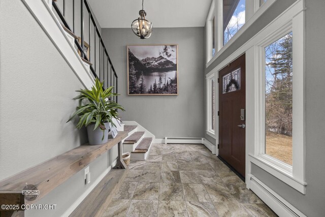 entryway with a notable chandelier, a baseboard heating unit, and a wealth of natural light