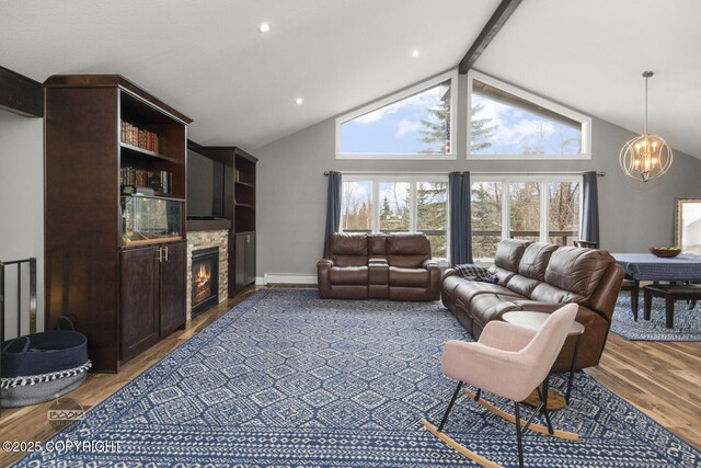 living area featuring wood finished floors, beam ceiling, a stone fireplace, a baseboard heating unit, and a notable chandelier
