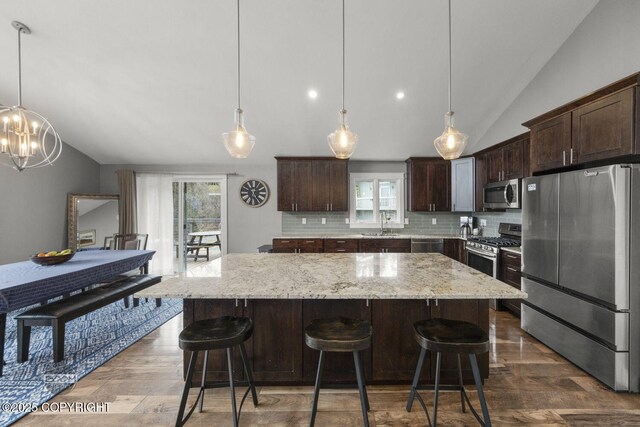 kitchen with appliances with stainless steel finishes, tasteful backsplash, and vaulted ceiling