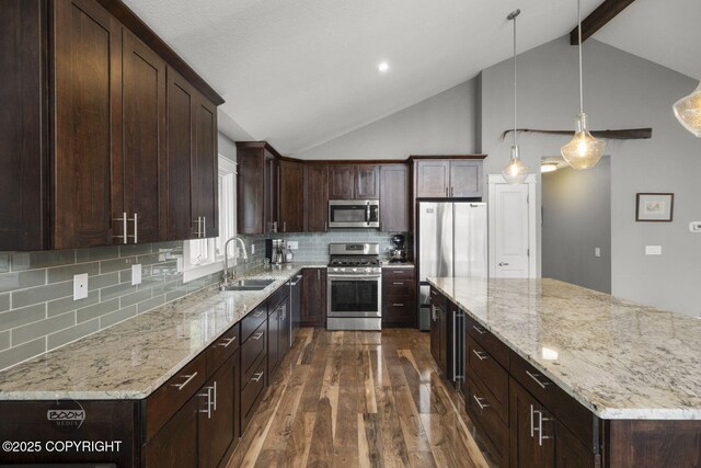 kitchen with a kitchen island, dark wood-style flooring, appliances with stainless steel finishes, light stone countertops, and a sink