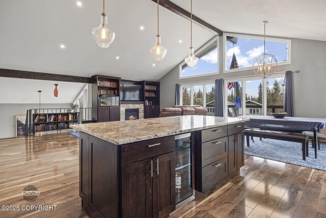 kitchen featuring wood finished floors, wine cooler, beam ceiling, and a fireplace