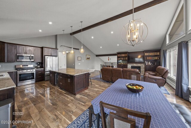 dining room featuring a fireplace, a chandelier, beam ceiling, and dark wood-type flooring