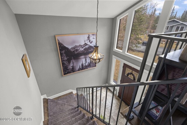 stairs featuring an inviting chandelier and baseboards