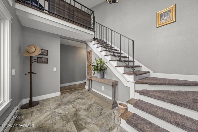 stairway with baseboards, stone finish floor, and a baseboard radiator