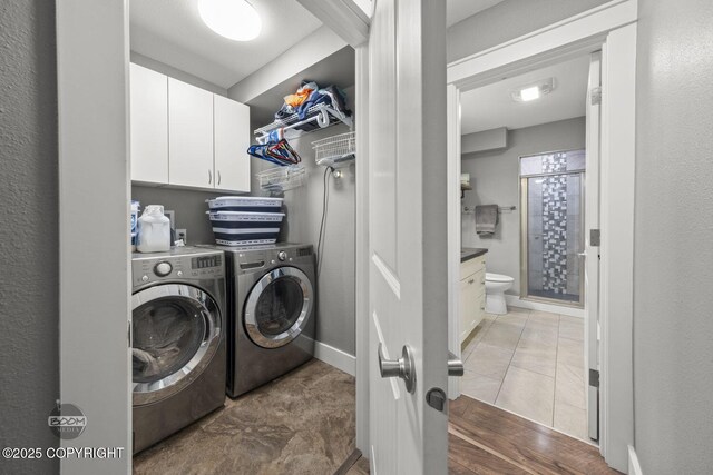 laundry room featuring baseboards, cabinet space, and washer and dryer