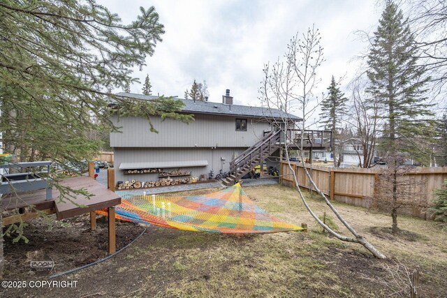 rear view of property featuring fence, a wooden deck, a chimney, and stairway