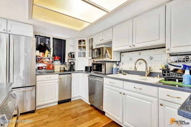 3210 Seawind Dr, Anchorage, AK 99516 - kitchen featuring appliances with stainless steel finishes, a sink, light wood finished floors, white cabinetry, and tasteful backsplash