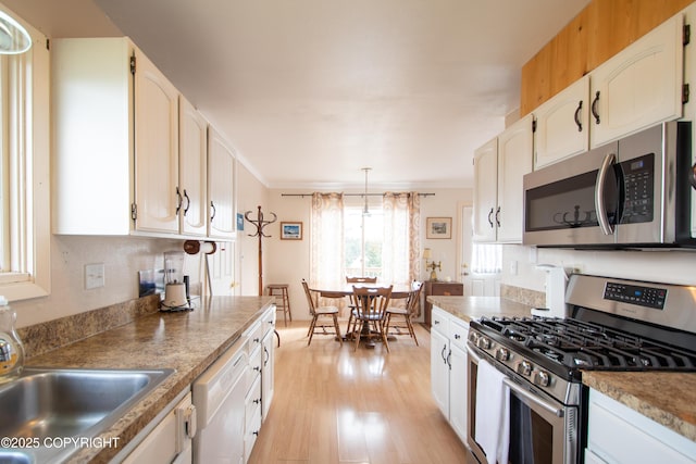 414 Bonanza Ave, Homer, AK 99603 - kitchen featuring appliances with stainless steel finishes, light wood-type flooring, a sink, white cabinetry, and decorative light fixtures