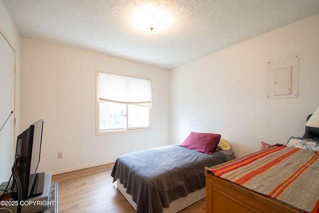 414 Bonanza Ave, Homer, AK 99603 - bedroom with light wood-type flooring, electric panel, a textured ceiling, and baseboards