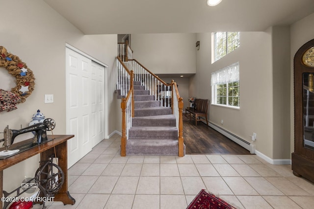 stairway with a baseboard heating unit, tile patterned flooring, and baseboards