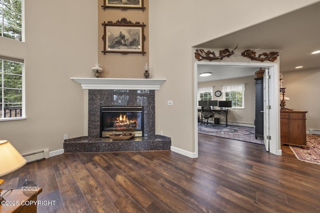 unfurnished living room with a baseboard radiator, wood finished floors, a high end fireplace, recessed lighting, and baseboards