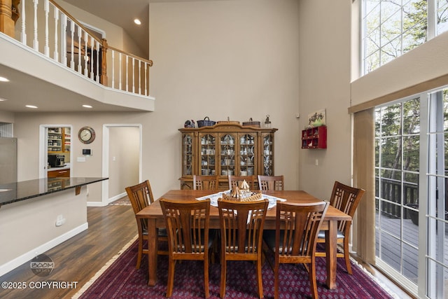 dining area featuring a towering ceiling, dark wood-type flooring, baseboards, and recessed lighting