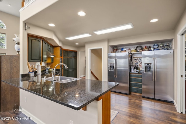 kitchen featuring stainless steel refrigerator with ice dispenser, a sink, a peninsula, open shelves, and recessed lighting