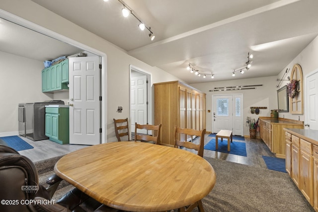 dining space featuring rail lighting, wood finished floors, baseboards, washer and dryer, and french doors