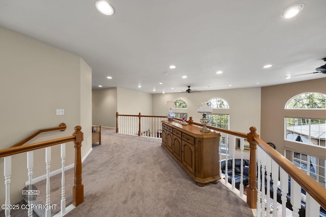hallway with an upstairs landing, recessed lighting, light colored carpet, and baseboards