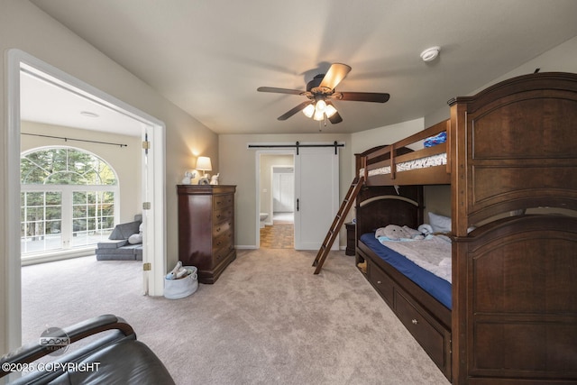 bedroom featuring light colored carpet, a barn door, ceiling fan, and baseboards