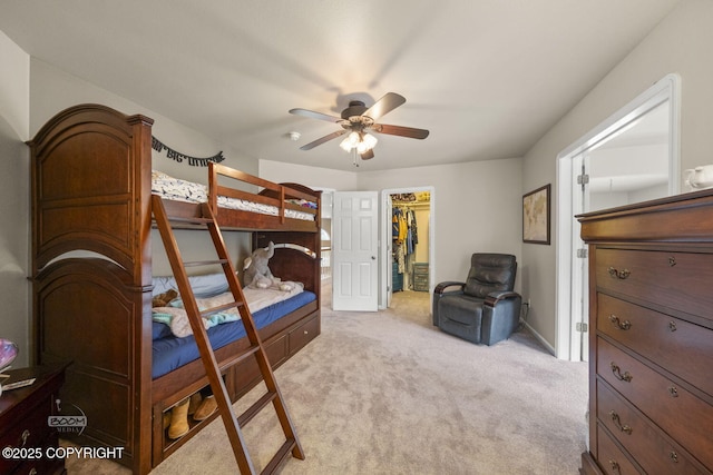 bedroom featuring light colored carpet, a walk in closet, a closet, and a ceiling fan