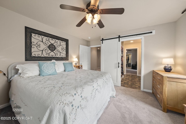 bedroom with a barn door, light colored carpet, baseboards, and ceiling fan