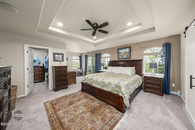 bedroom featuring light carpet, multiple windows, recessed lighting, a walk in closet, and baseboards