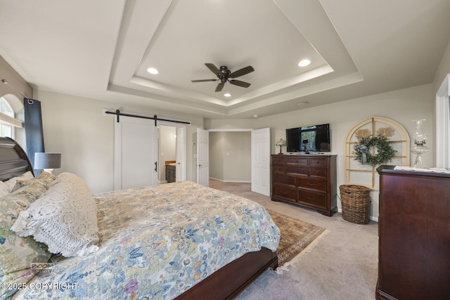 bedroom featuring light carpet, a raised ceiling, a barn door, recessed lighting, and ceiling fan