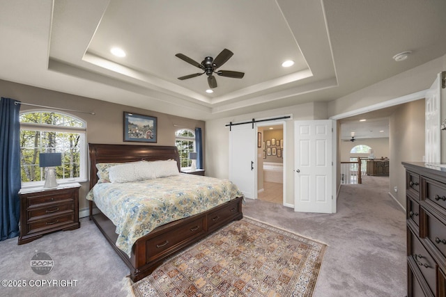 bedroom with light colored carpet, a tray ceiling, a barn door, recessed lighting, and baseboard heating