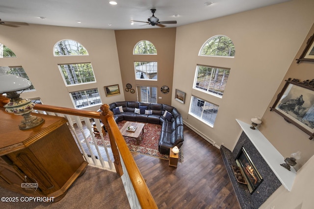 living area with ceiling fan, healthy amount of natural light, a tile fireplace, a towering ceiling, and recessed lighting