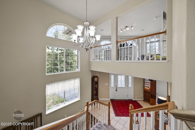foyer entrance featuring a high ceiling, a chandelier, a baseboard radiator, baseboards, and tile patterned floors