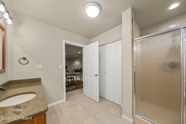 full bathroom with vanity, tile patterned flooring, a shower stall, and baseboards