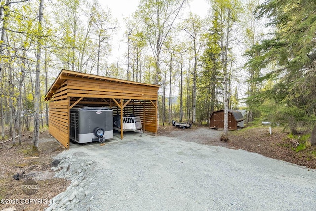garage with a carport, dirt driveway, a storage shed, and ac unit