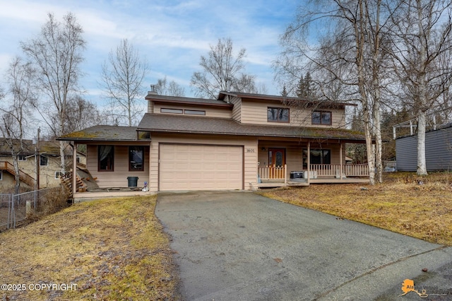 traditional home featuring aphalt driveway, fence, covered porch, roof with shingles, and an attached garage