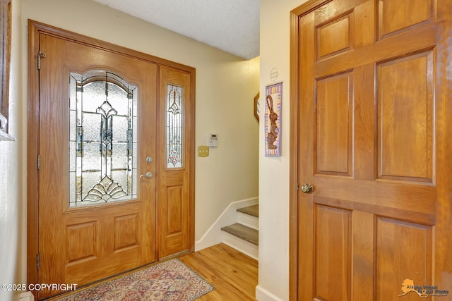 foyer featuring stairs, baseboards, and light wood-type flooring