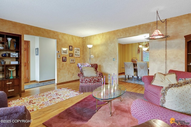 living area with baseboards, wood finished floors, and a chandelier
