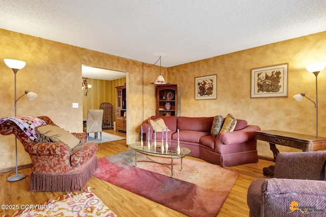 living area with a textured ceiling, wood finished floors, and a chandelier