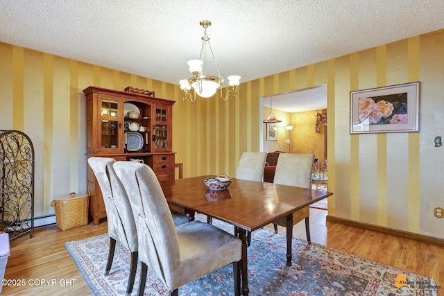 dining area featuring light wood-type flooring, wallpapered walls, a textured ceiling, and a notable chandelier