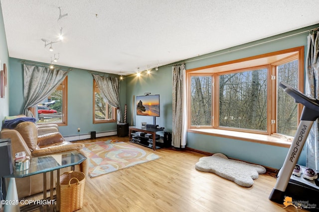 living area with baseboards, a baseboard radiator, a textured ceiling, and wood finished floors