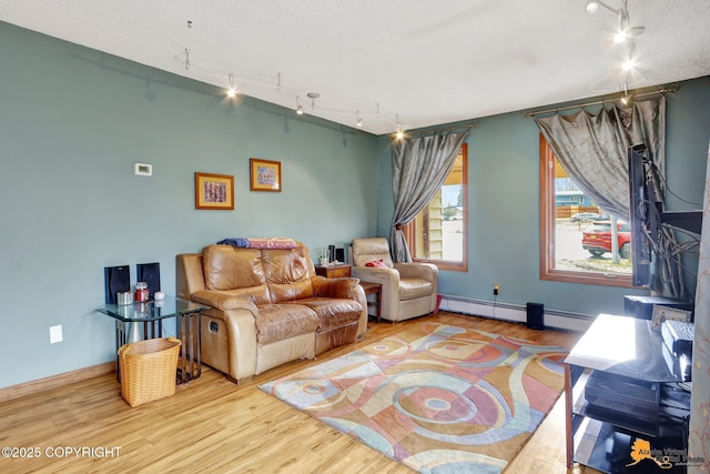 living area featuring baseboards, baseboard heating, rail lighting, and wood finished floors