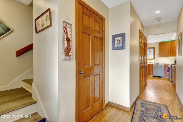 hall featuring baseboards, recessed lighting, light wood-style flooring, and stairway