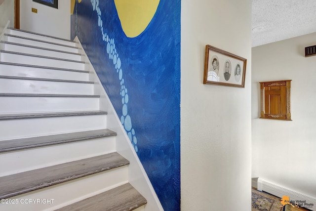 staircase with a textured ceiling and baseboard heating